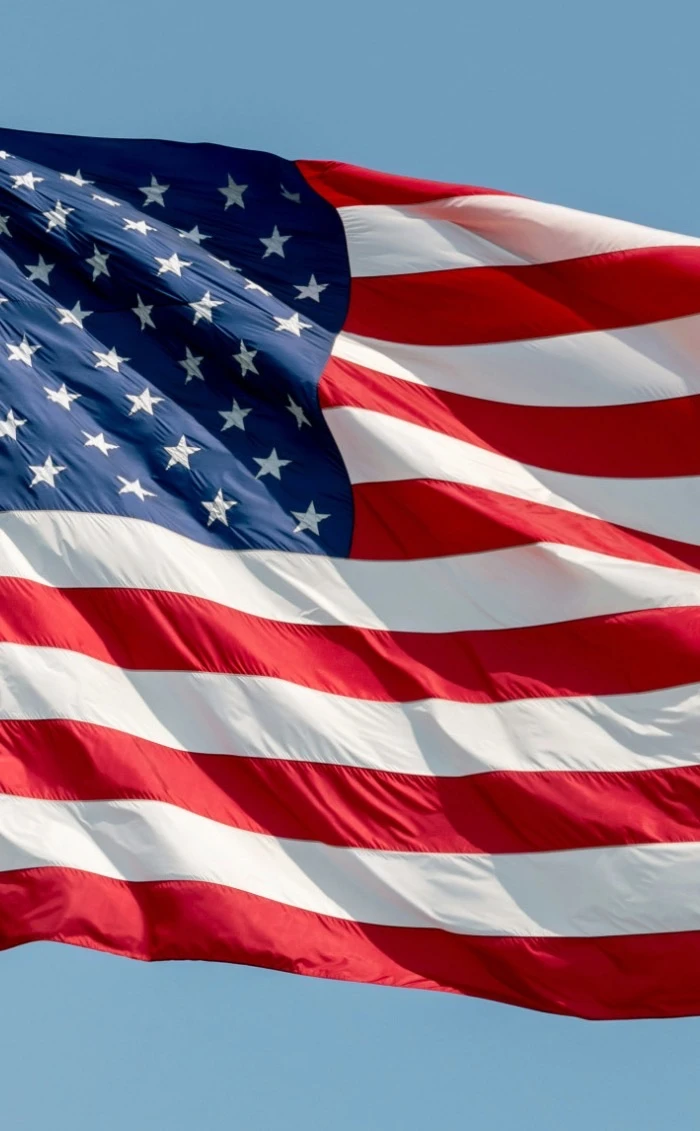 The flag of the United States flying against a blue sky.