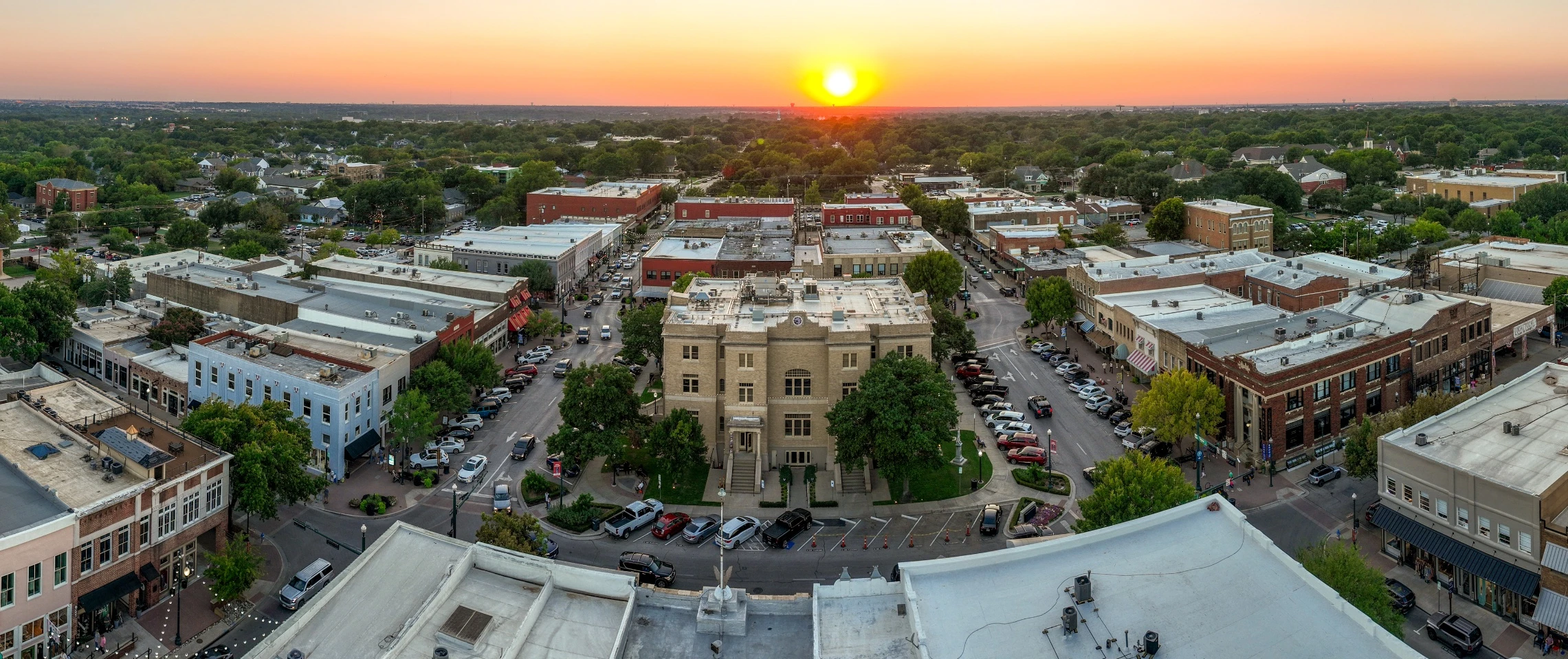 An aerial view of the historic courthouse in downtown McKinney at sunset.
