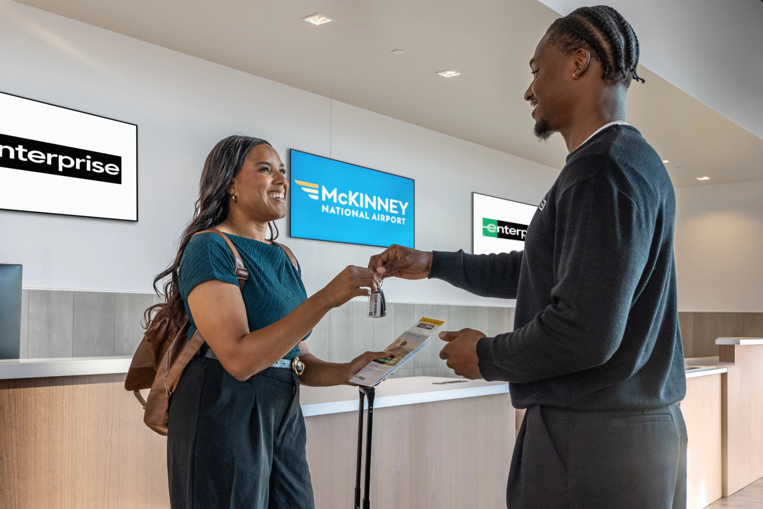 A traveler takes the keys to her rental car from an agent at the Enterprise counter in the terminal.