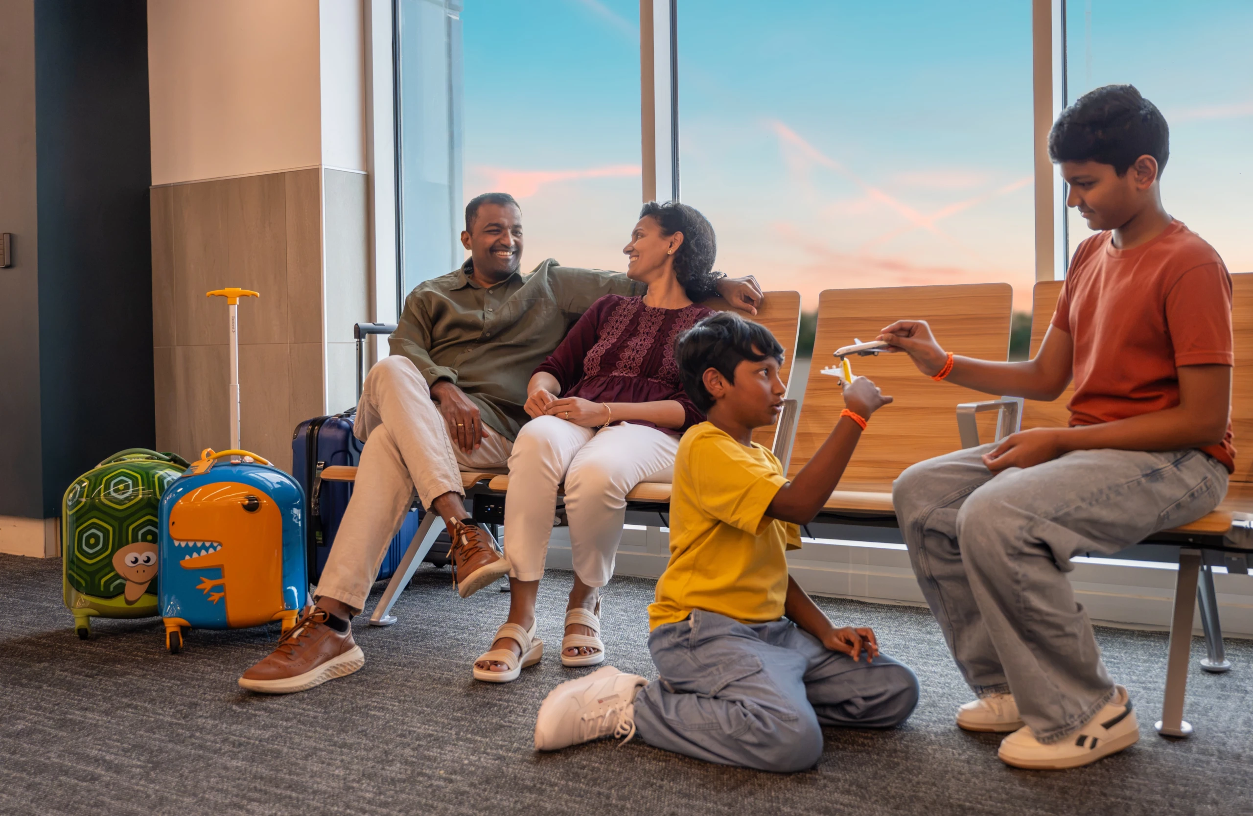 A family relaxing in the gate seating at McKinney National Airport, the children playing with a toy airplane.
