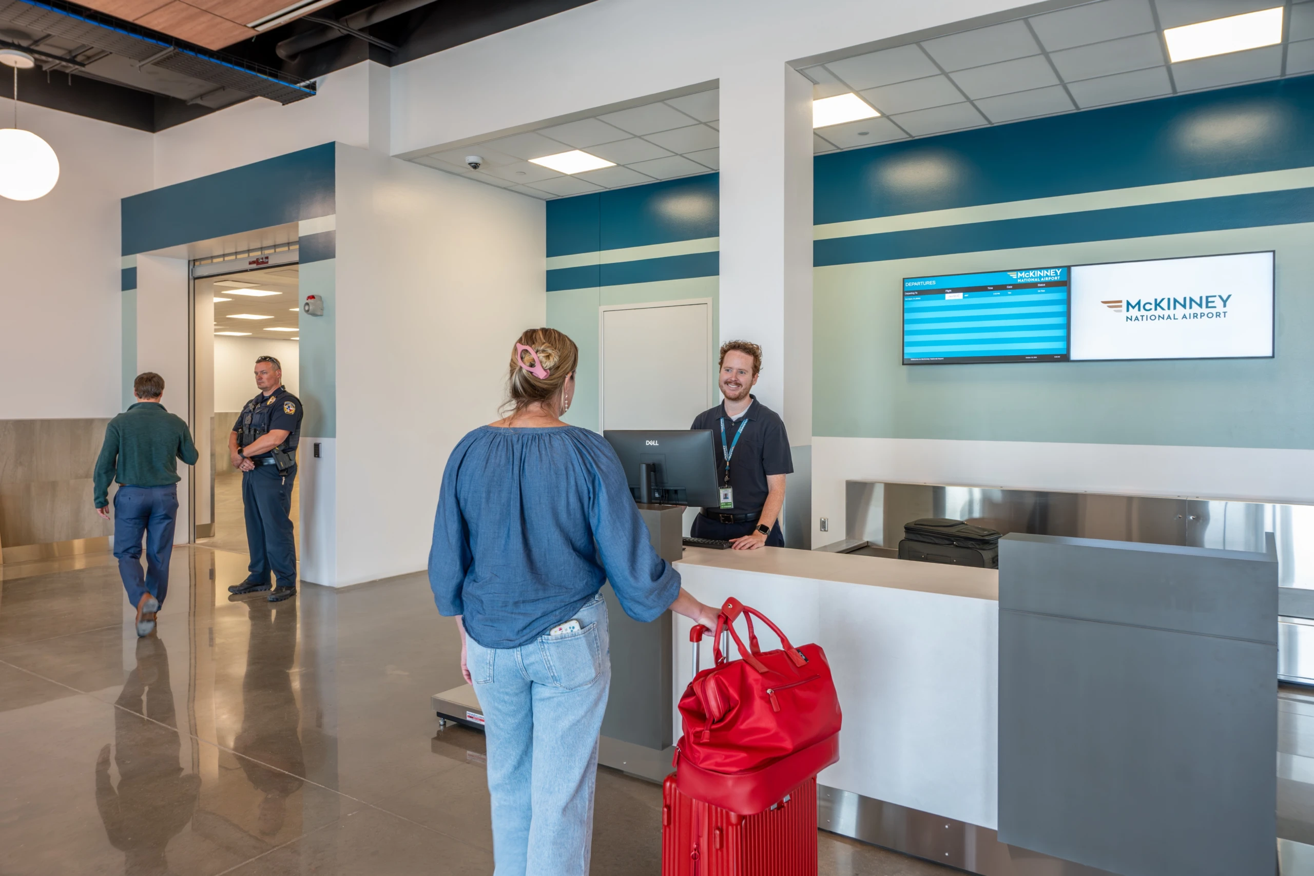 A traveler with a red bag checks in with an agent at the McKinney National Airport ticket counter.
