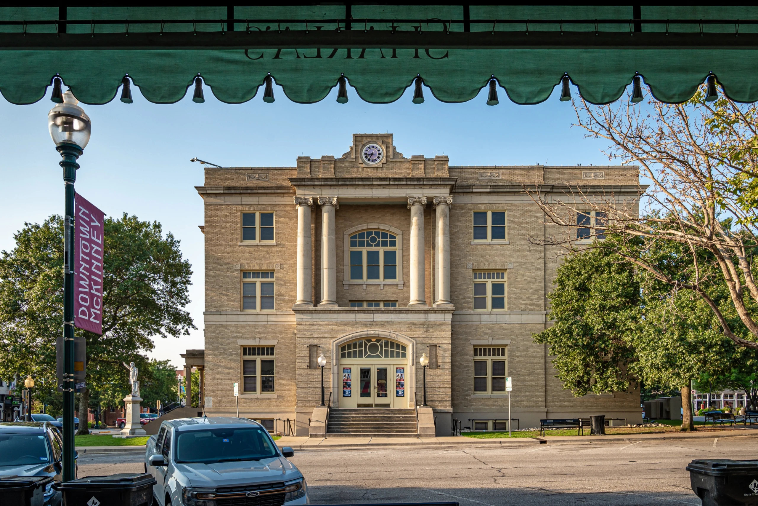 The McKinney Performing Arts Center, the historic former courthouse on the downtown square, seen from under a shop awning.